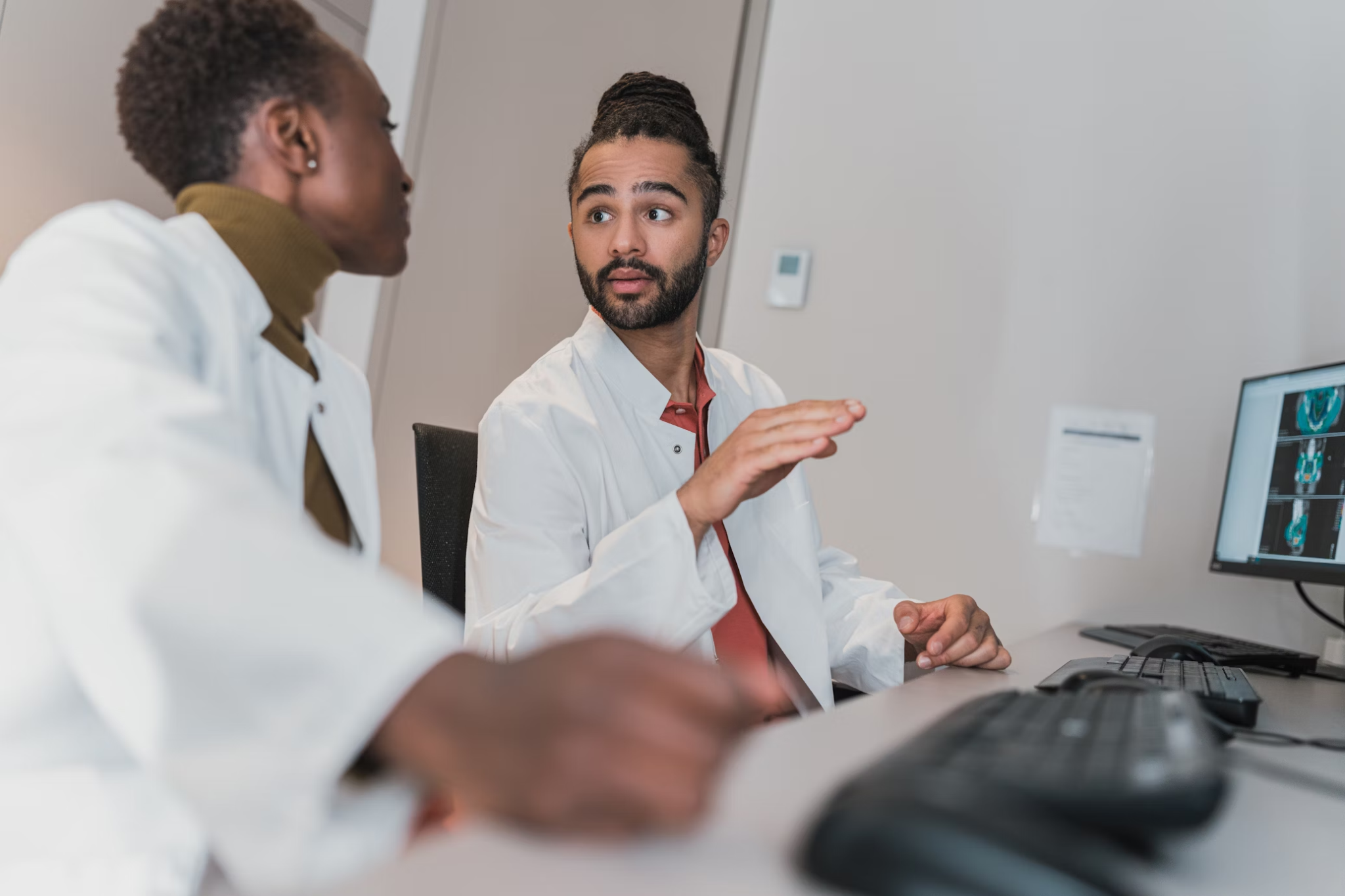 Two forensic experts having a discussion in front of a computer monitor